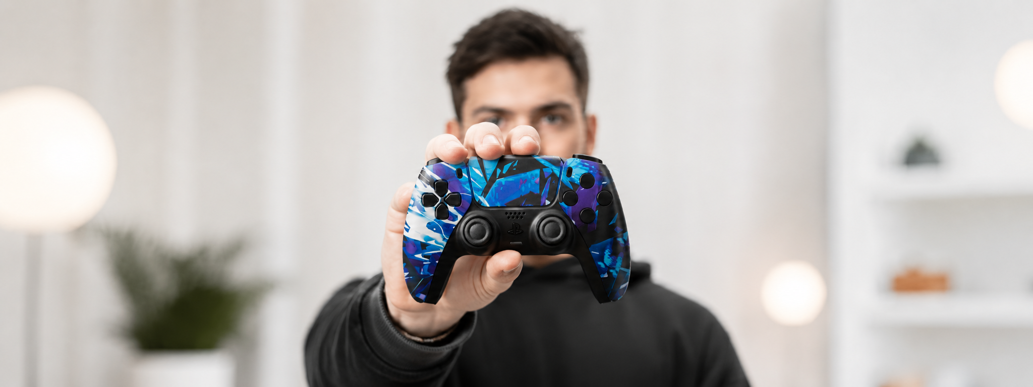 Custom PS5 Controller mit blau-lila Design von INFINITE GAMES wird in die Kamera gehalten